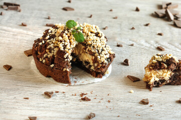 Appetizing cake with chocolate and nuts, decorated with mint with chocolate chips on a gray wooden table. selective focus