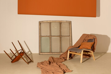 Photo studio interior in orange colors with window frame, chairs, paper and textile backgrounds.