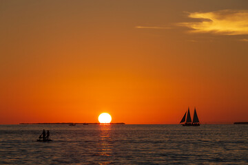 The famous sunset in Key West is really beautiful, seabirds flying, golden sky as background, boats...