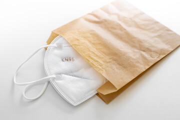 Generic KN95 (FFP2) white facemask stored inside a paper bag to quarantine and sanitize prior to...