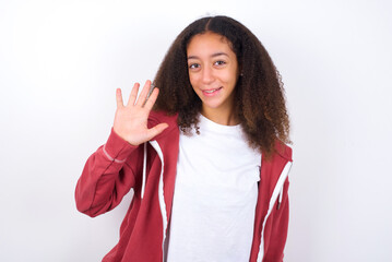teenager girl wearing pink jacket standing against wite background Waiving saying hello happy and smiling, friendly welcome gesture.