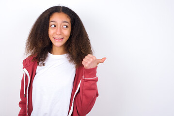 Charming teenager girl wearing pink jacket standing against wite background looking at copy space having advertisements