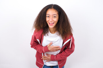 teenager girl wearing pink jacket standing against wite background smiling and laughing hard out...