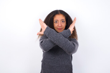 teenager girl wearing grey sweater standing against wite background Rejection expression crossing arms doing negative sign, angry face