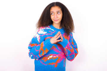 beautiful teenager girl wearing colorful sweater standing against wite background  steepls fingers and looks mysterious aside has great evil plan in mind