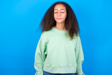 Fototapeta na wymiar beautiful teenager girl wearing green sweater standing against blue background nice-looking sweet charming cute attractive lovely winsome sweet peaceful closed eyes