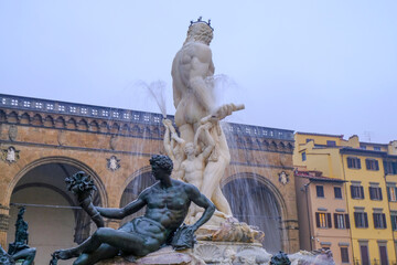 Florence, Italy: the Neptune Fountain on the square piazza della Signoria near the Palace Vecchio in old town in the evening across windows lights