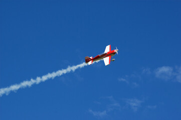 Model of acrobatic airplane flying in a blue sky - obrazy, fototapety, plakaty