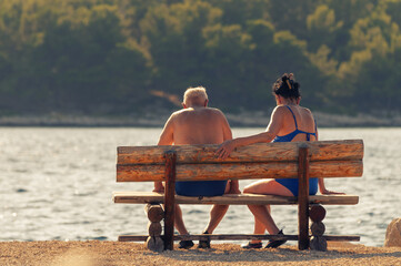Senior couple sitting on the bench by the sea