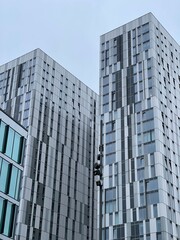 Fototapeta premium Looking up at modern buildings with a grey sky background. Taken in Salford Quays England. 