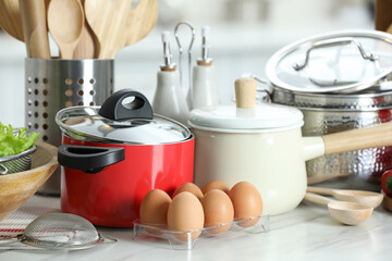 Set of cooking utensils and products on white table against blurred background