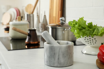 Marble mortar with pestle on kitchen counter. Cooking utensils