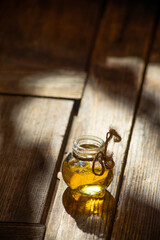 A small round glass jar of honey stands on an old shabby wooden table.