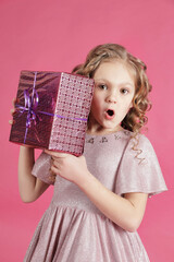 Cute girl with blonde hair holding a gift box,surprised face