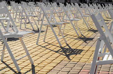 White folding chairs are placed on the square on the pavement. Quarantine restrictions, mass events, a concert on the street