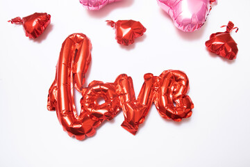 Festive background for Valentines Day from foil balloons shape heart and love word on white background