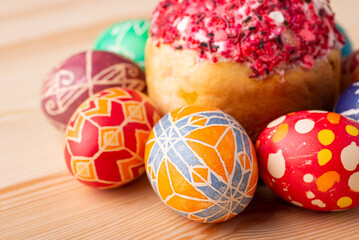 Close-up photo of painted Easter eggs near Easter bread on wooden table. Traditional celebration of Eastertime in Ukraine