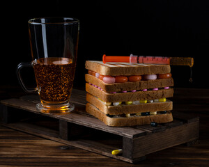 sandwich with pills and a glass of mixture on a dark background