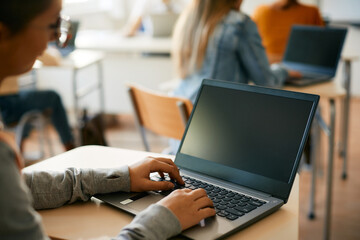 Close-up of high school student using laptop during computer class at school.