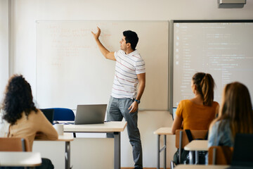 Male professor giving lecture during IT class in the classroom at high school.