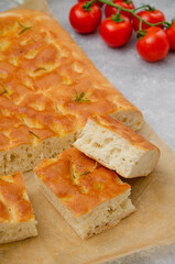 Traditional Italian Focaccia with rosemary, garlic, sea salt and olive oil on a gray concrete background.