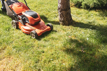 the process of cutting the grass on the lawn with an orange mower