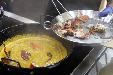 chef preparando una paella de arroz con bogavante y marisco
