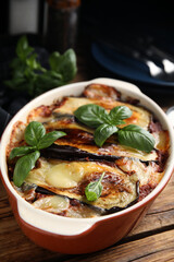 Delicious eggplant lasagna in baking dish on wooden table