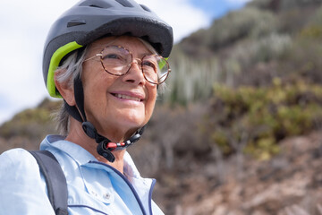 Close up portrait of active adult smiling senior woman wearing sport helmet and eyeglasses in...