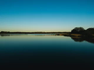 Foto op Canvas zonsondergang over het meer © emilian.dk