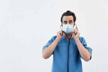 thoughtful physician in medical mask using stethoscope isolated on grey.