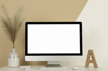Modern computer, decor and office supplies on white wooden table near color wall