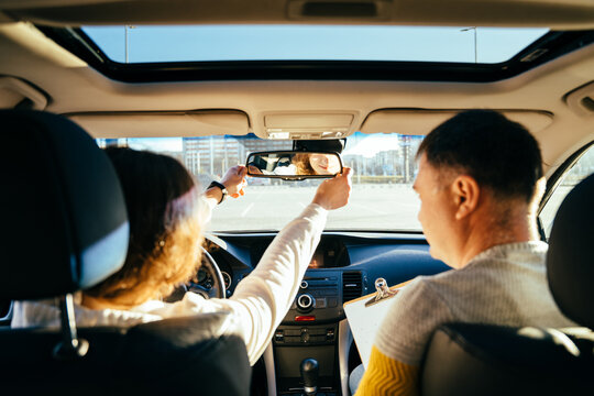 Close Up Of Female Hands Correcting Mirror. Traveler Girl On Car Trip, Looking At The Road. View Over Shoulder Female On Test Drive Car With Instructor