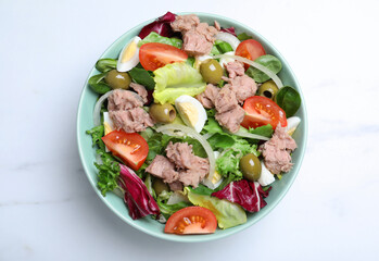 Bowl of delicious salad with canned tuna and vegetables on white marble table, top view