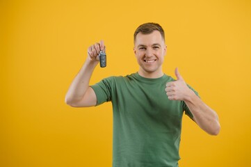 man with car keys on a yellow background, buying a new car