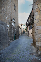 A typical cobbled street of the city, under a cloudy sky, Tuscania, Tuscia, Lazio, Italy