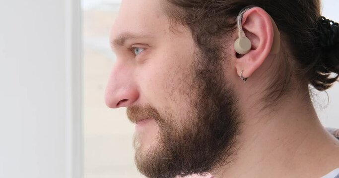Handsome man wearing hearing aid while listening and shaking head