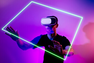 Man in metaverse using VR virtual reality glasses. Futuristic universe games and future in digital technology. Entreatment and NFT in neon colorful space. Happy male. Slow motion video in 3d cyber.
