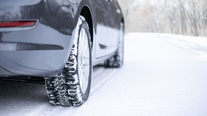 Car on the Winter Road. Close-up Image of Winter Car Tire on the Snowy Road. Safe Driving Concept.