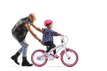 Little girl trying to ride a bicycle and a man holding the bike