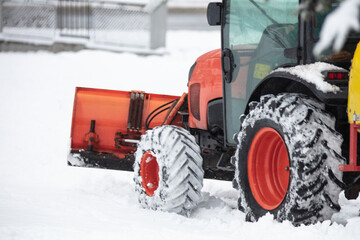 Tractor cleaning urban park paths on a cold snowy day.