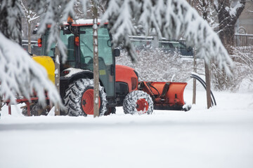 Fototapeta na wymiar Tractor cleaning urban park paths on a cold snowy day.