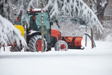 Tractor cleaning urban park paths on a cold snowy day.