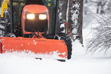 Tractor cleaning urban park paths on a cold snowy day.