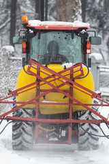 Tractor cleaning urban park paths on a cold snowy day.