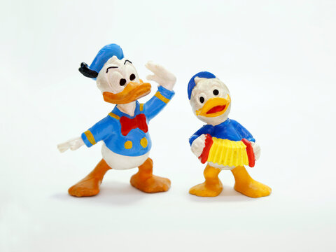 Donald Duck and one of his nephews playing the accordion.  Huey, Dewey, and Louie. Cartoon characters from Walt Disney. Classic cartoon. Isolated white. Retro plastic doll. Vintage. Sailor. Toys.