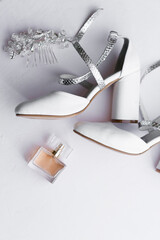 Luxury perfume bottle, white heels, hairpin, on white background, top view. Preparation for wedding