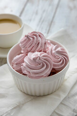 Pink Meringue marshmallow zephyr in a white bowl on a white wooden table.