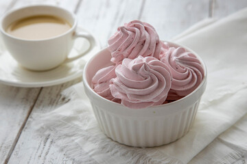 Pink Meringue marshmallow zephyr in a white bowl on a white wooden table.