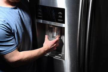 Home fridge dispenser filling glass held by male at night